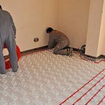 работники укладывают теплый пол